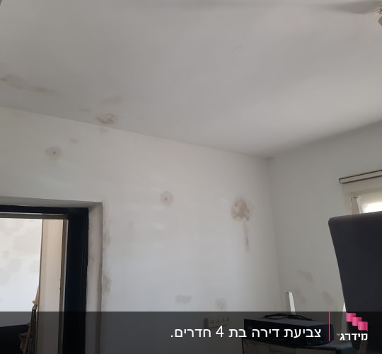 קיר עם תיקוני צבע וטיח, נורה תלויה מהתקרה